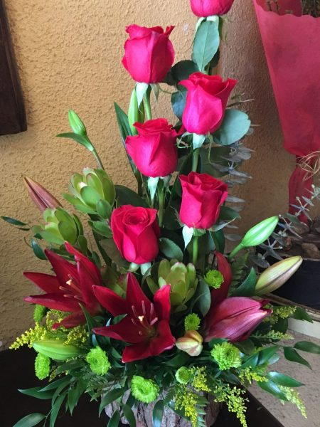 Base de madera con rosas rojas y lilium